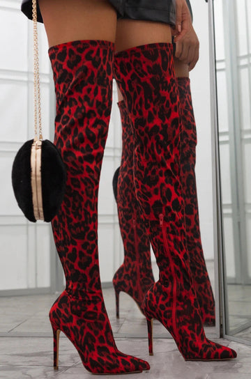 Zaria Red Leopard over-the-knee stiletto boots worn on a model, featuring a bold red and black leopard print, fitted thigh-high silhouette, sleek pointed toes, and tall slim stiletto heels for a dramatic Fall and Winter statement look.